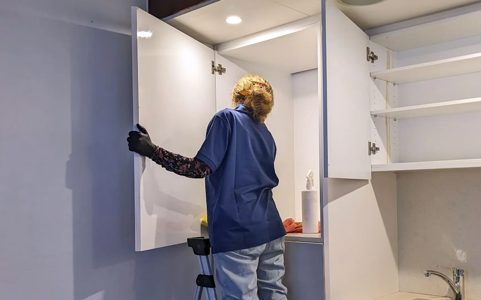 Cleaner wiping the interior of Perth rental kitchen cabinets